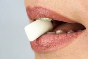 A plate of chewing gum in a woman's teeth close-up. Covidgum